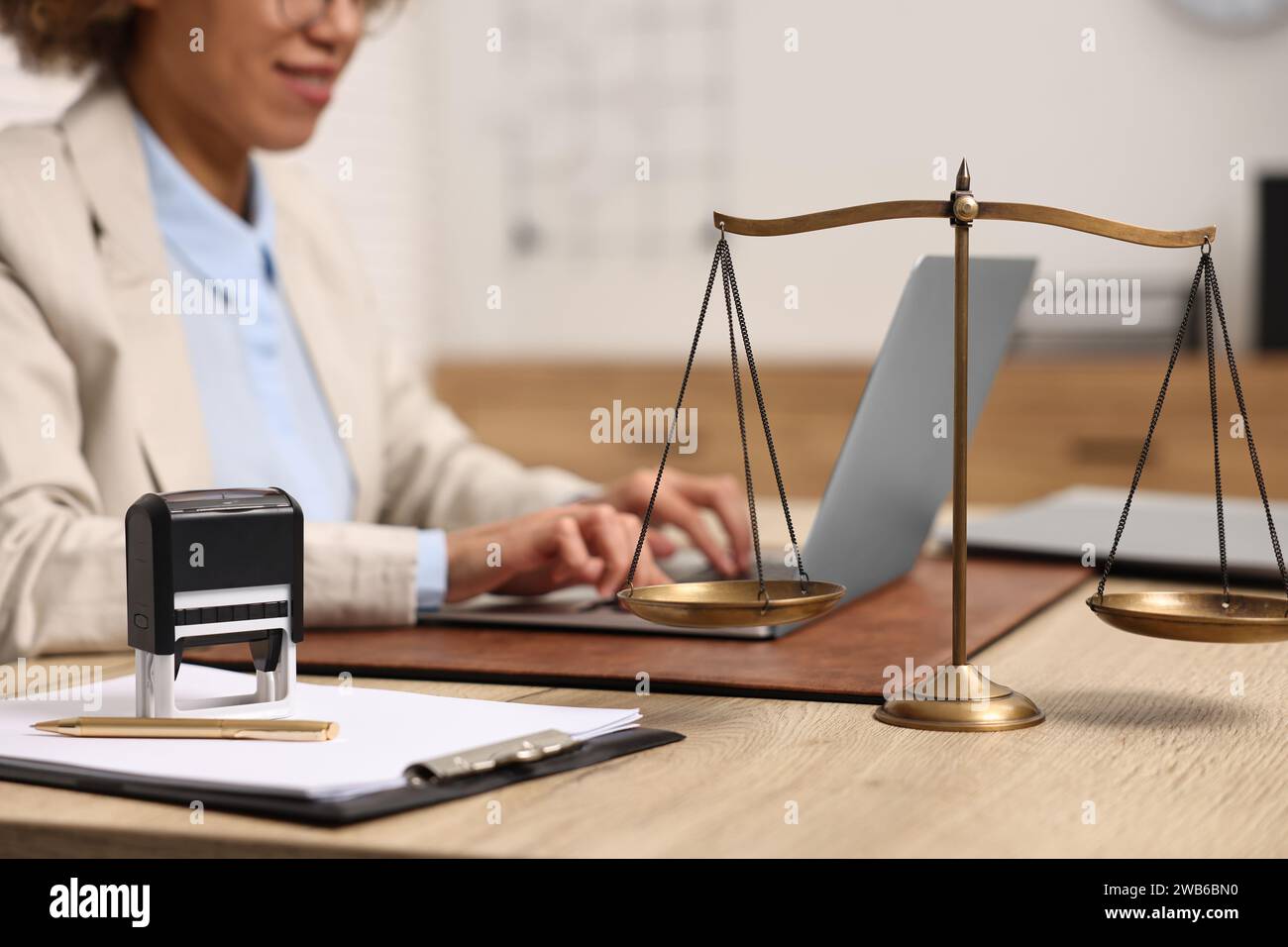Notary using laptop at workplace in office, focus on scales of justice ...