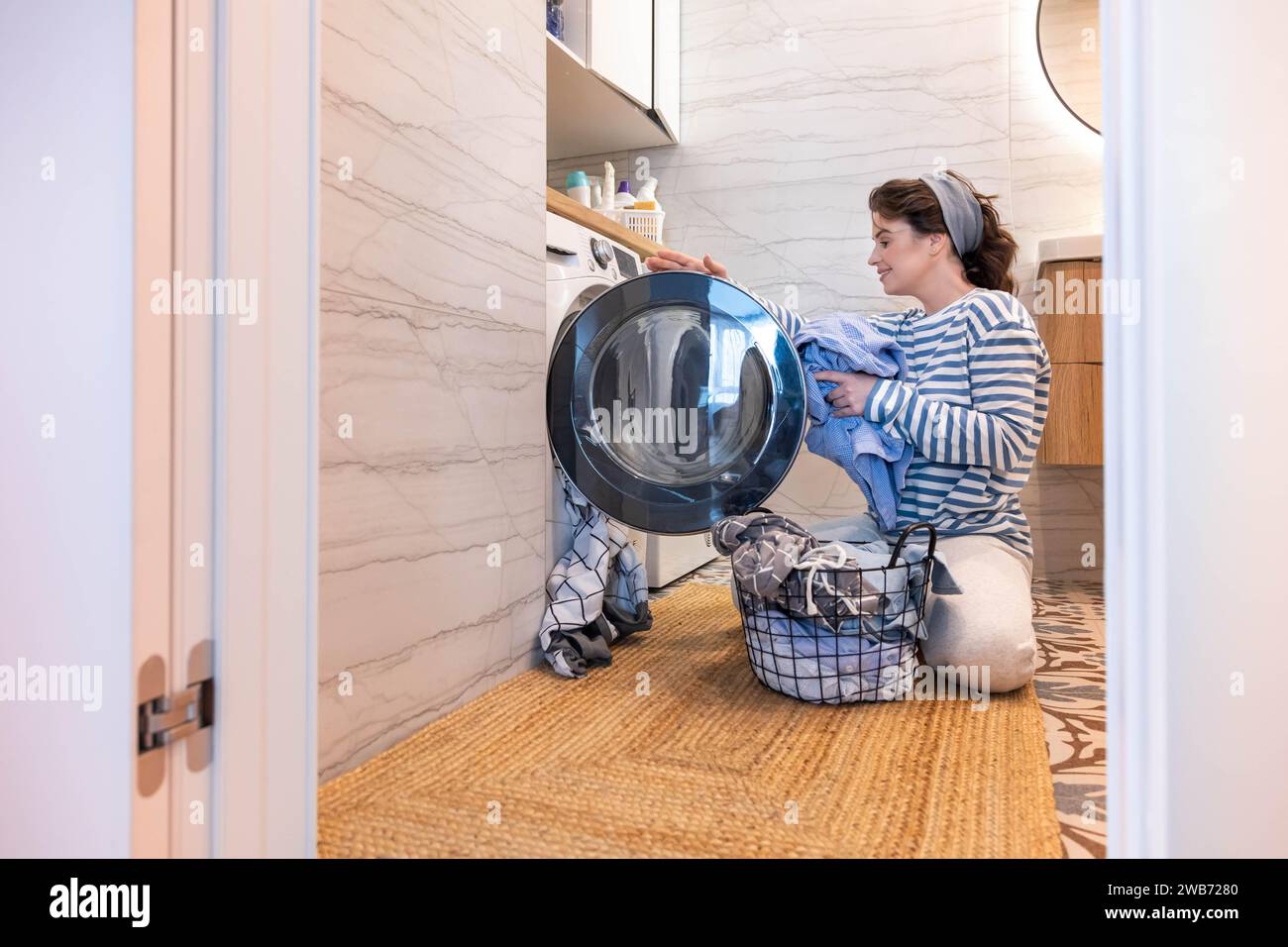 Smiling woman housewife cleaning linen textile clothes putting washing