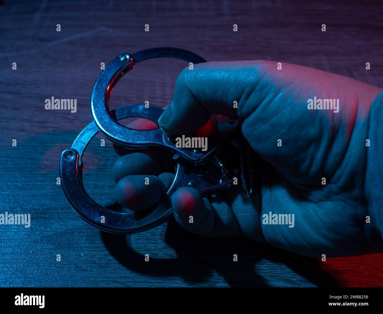 The man's hand holds handcuffs. Police handcuffs closeup Stock Photo
