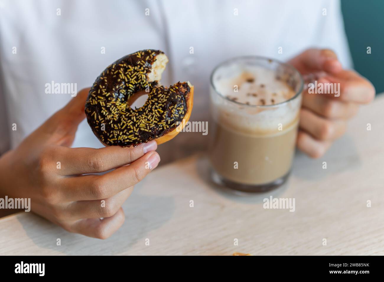 A Chocolate Donut being dipped in a hot coffee Stock Photo
