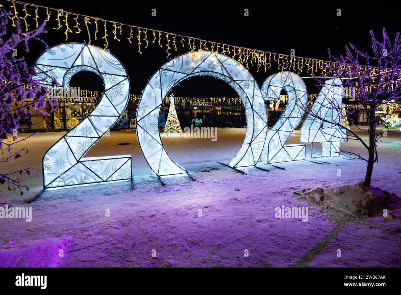 Happy New Year 2024. Sparkling burning numbers Year 2022 with on black background. Beautiful design element. christmas street decorations. snowfall mo Stock Photo