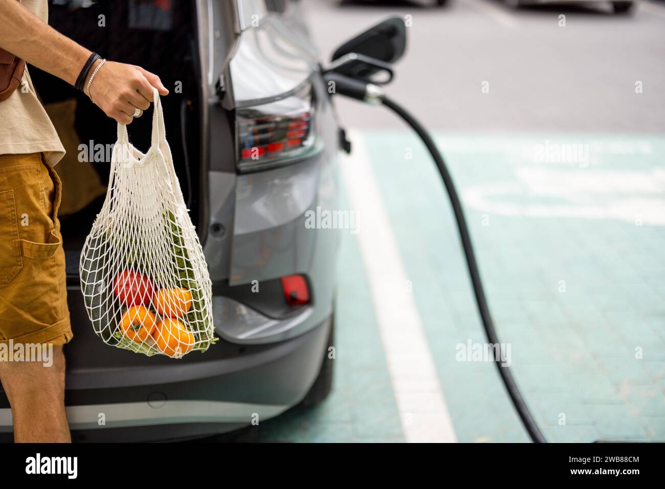 Man charging electric car while shopping Stock Photo