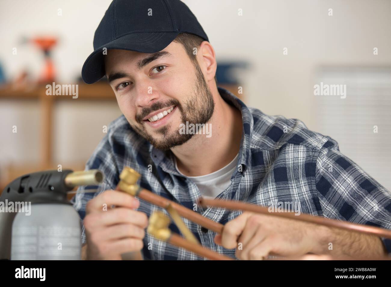 smiling plumber using welding gas torch to solder copper pipes Stock