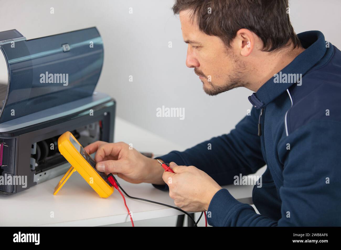 man testing broken printer with a multimeter Stock Photo