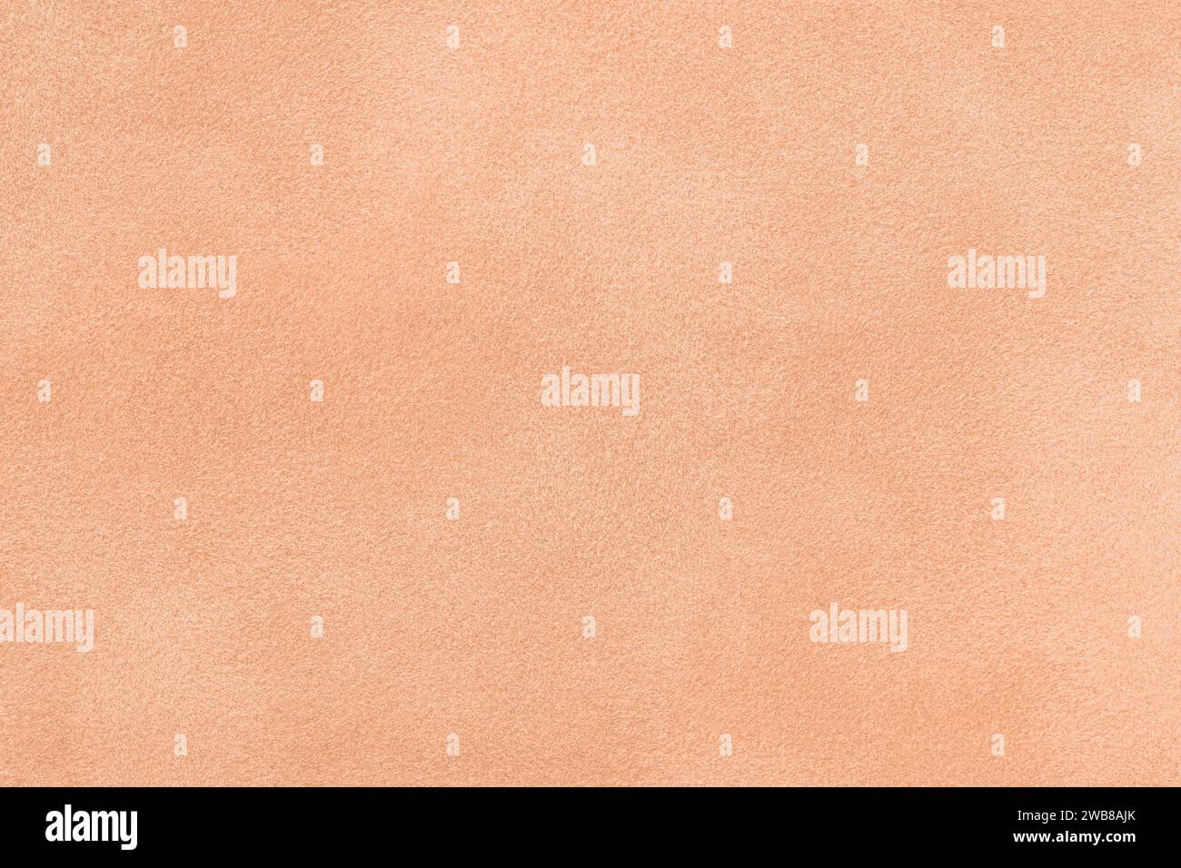 Color of year 2024 peach fuzz. Light coral matte background of suede fabric, closeup. Velvet texture of seamless textile, macro. Structure of red felt Stock Photo