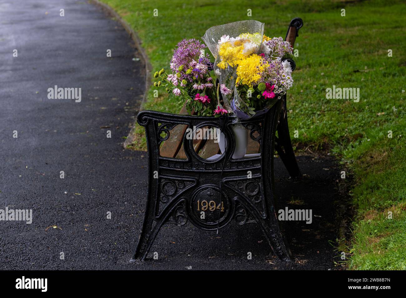 Bouquets of flowers placed on a memorial bench in a park in England in ...