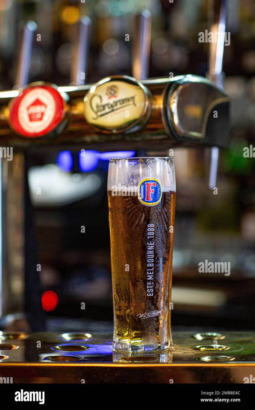 Fosters lager beer in original glass next to the tap . Stock Photo