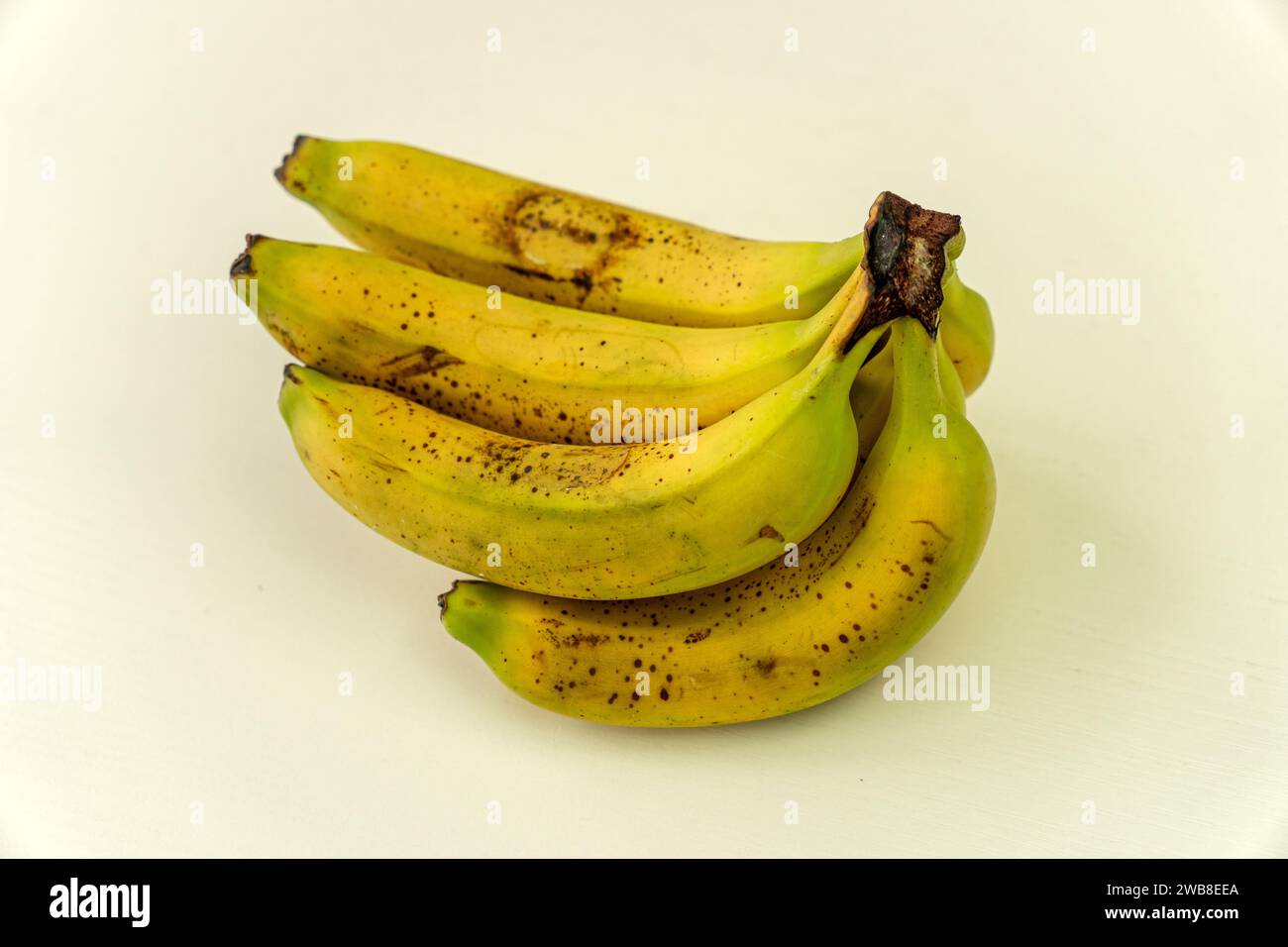 Ripe yellow bananas fruits, bunch of ripe bananas with dark spots on white background Stock Photo