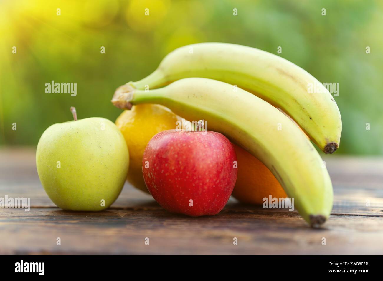 Still Life Fruits - Bananas and Apples on a wooden table against a blurred background of nature . Stock Photo