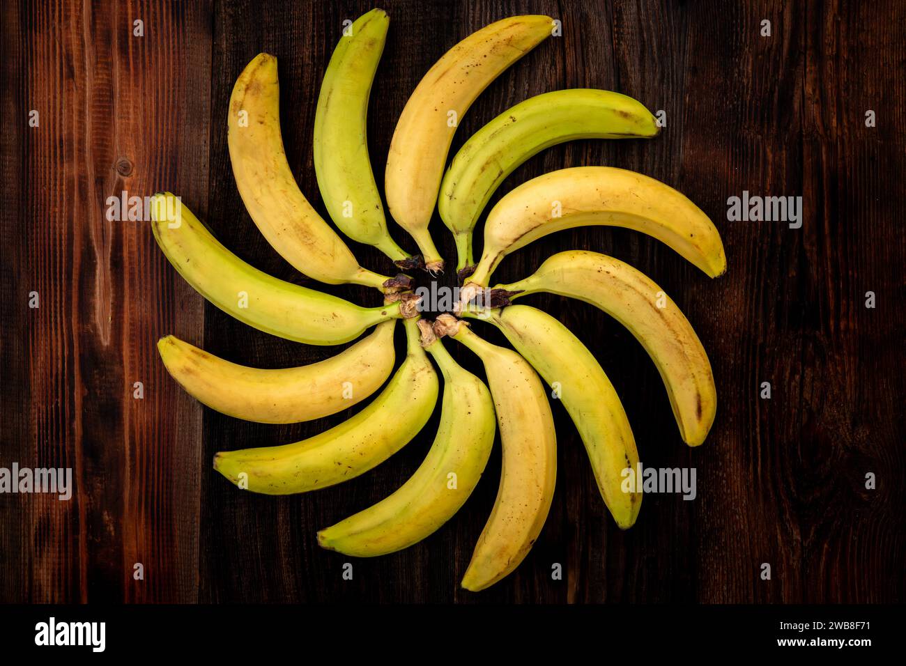 Bananas on brown wooden table top view. Figured position of bananas in geometric shape. bananas are laid out in the shape of the sun. Stock Photo