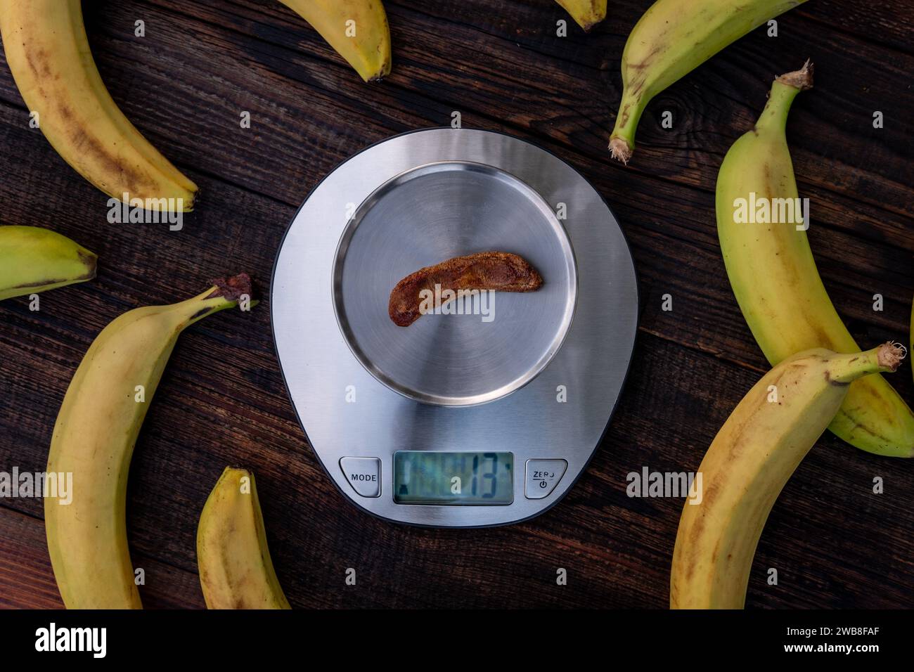 Ripe fresh and dried banana on the scales. Dread sweet on wooden background. concept of weight loss Stock Photo