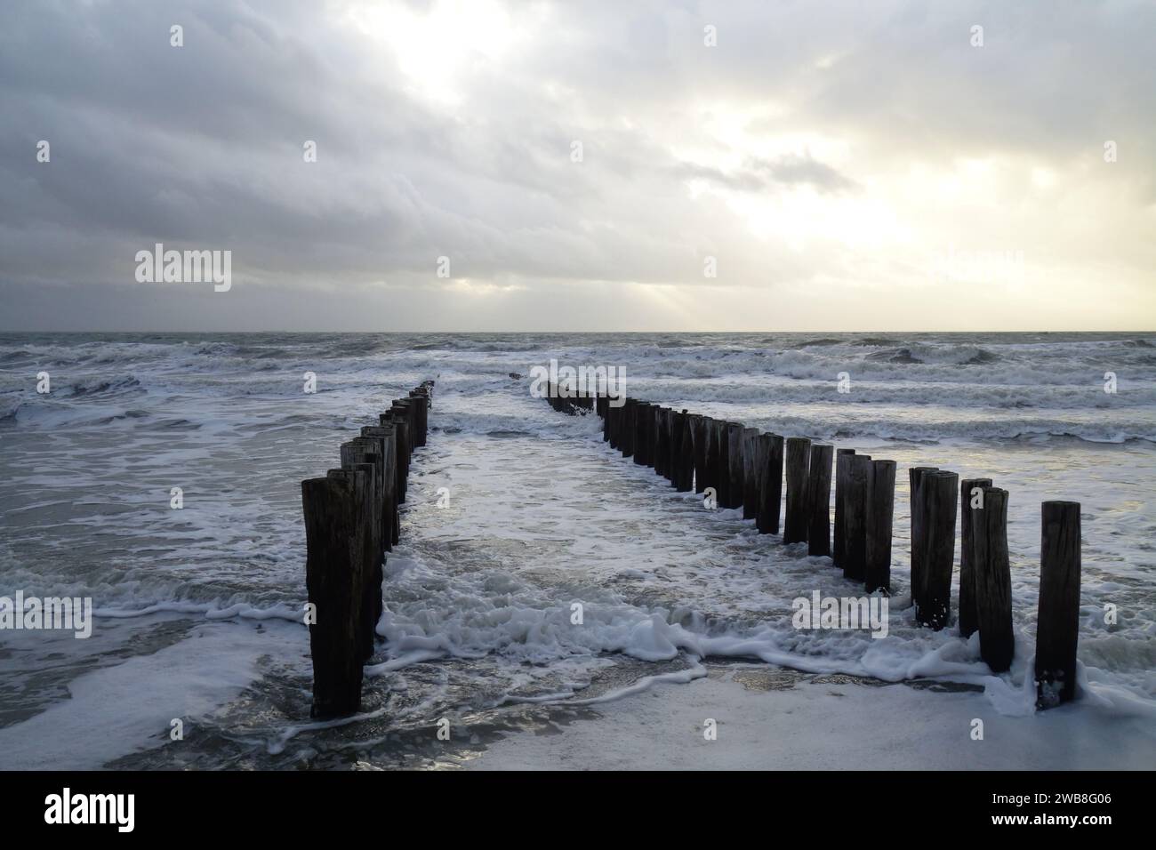 The lines of wooden posts extending out towards the ocean waters Stock Photo