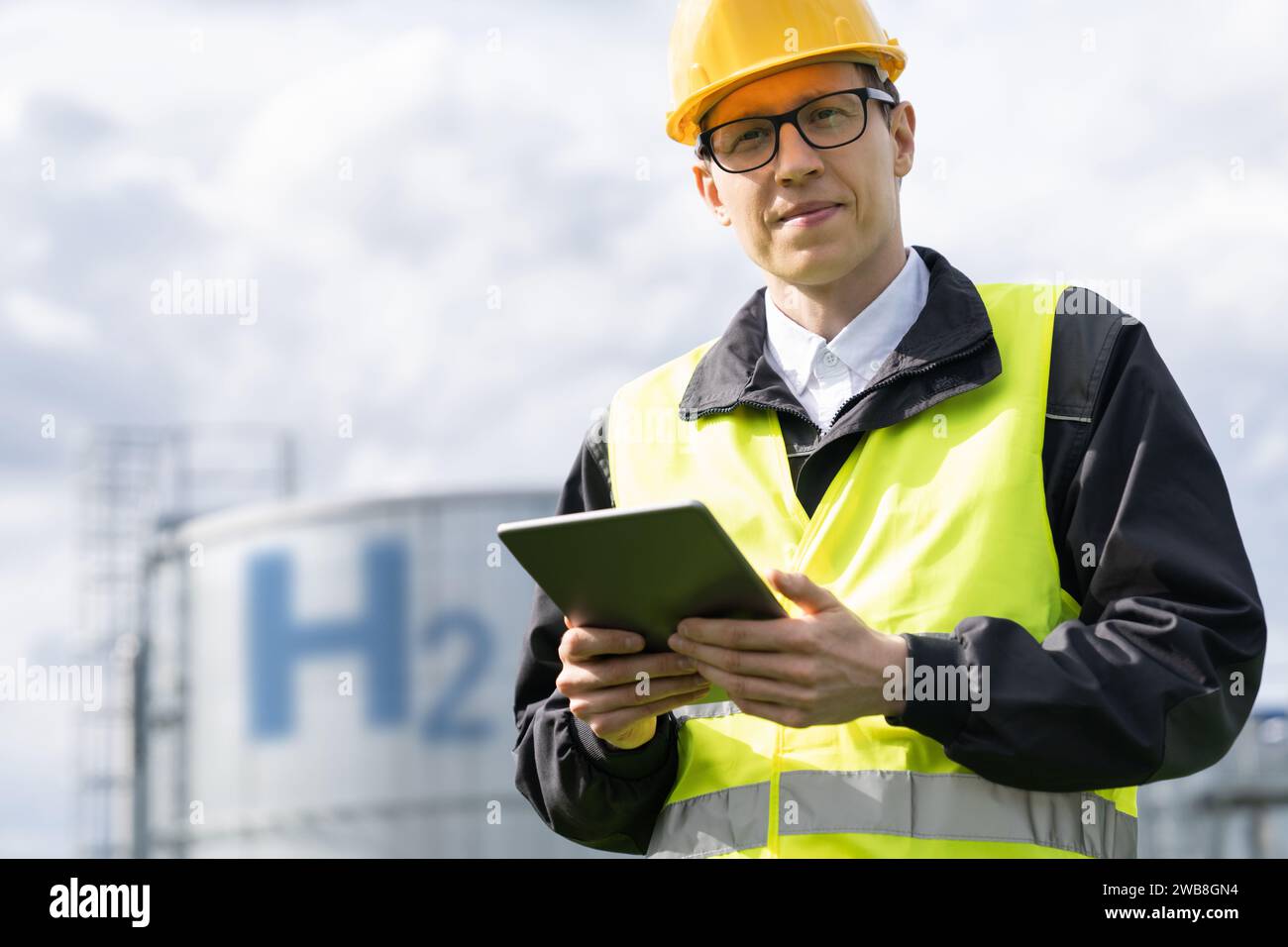 Engineer with tablet computer on a background of Hydrogen factory. Stock Photo