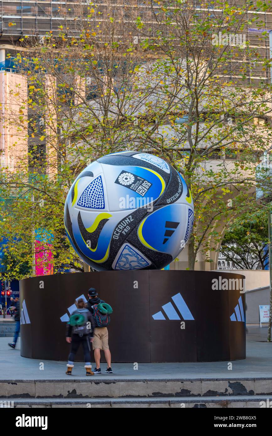 People looking at a giant 2023 FIFA Women's World Cup football mounted on an Adidas platform in Martin Place, Sydney, Australia Stock Photo