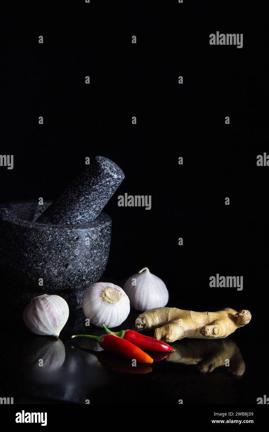 Fresh Single Clove Garlics and mortar, ginger and red chilli on black background with reflection Stock Photo