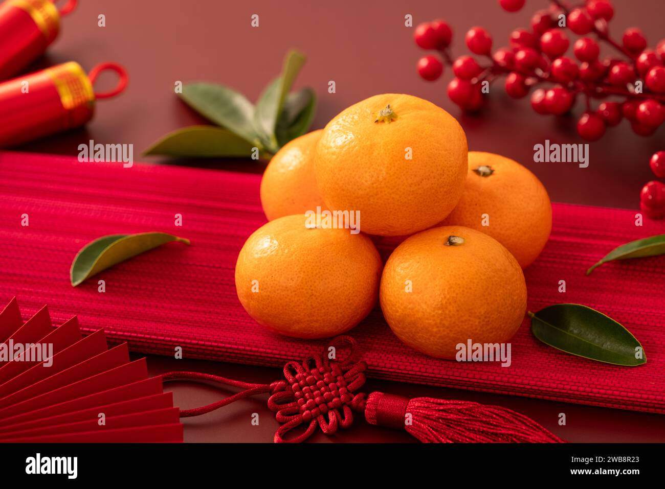Chinese lunar new year background with fresh tangerine, red envelope, paper fan and decorations for Spring Festival. Stock Photo