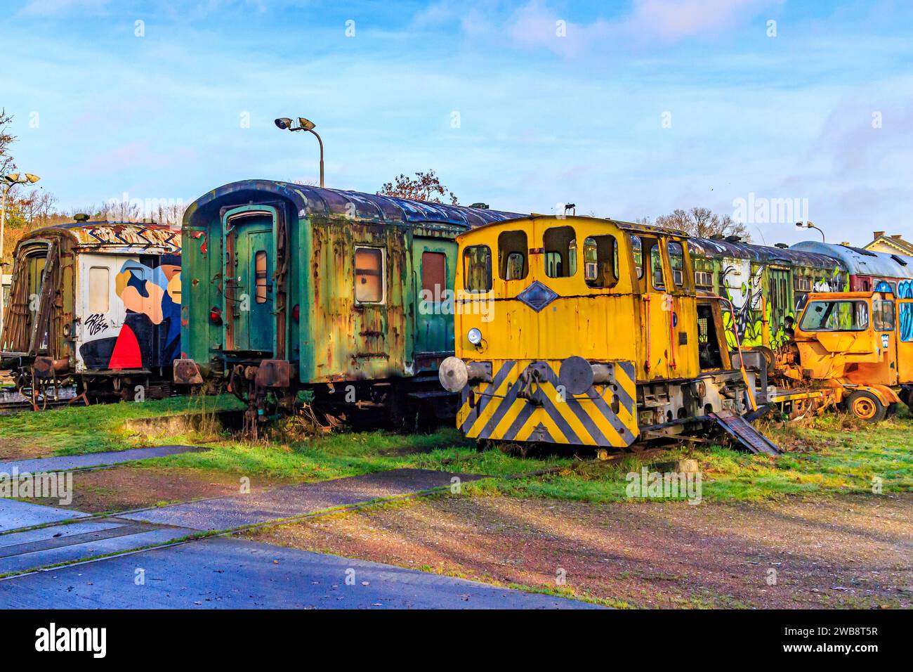 As, Limburg Belgium. December 17, 2023. Abandoned train carriages, in ruins, with graffiti and rusted by passage of time on disused tracks against blu Stock Photo