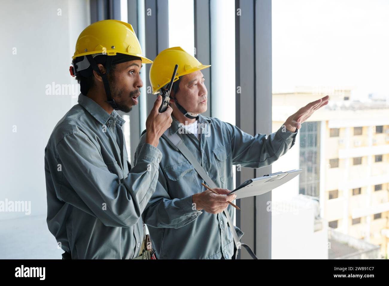 Construction worker using walkie-talkie to control work at construction site Stock Photo