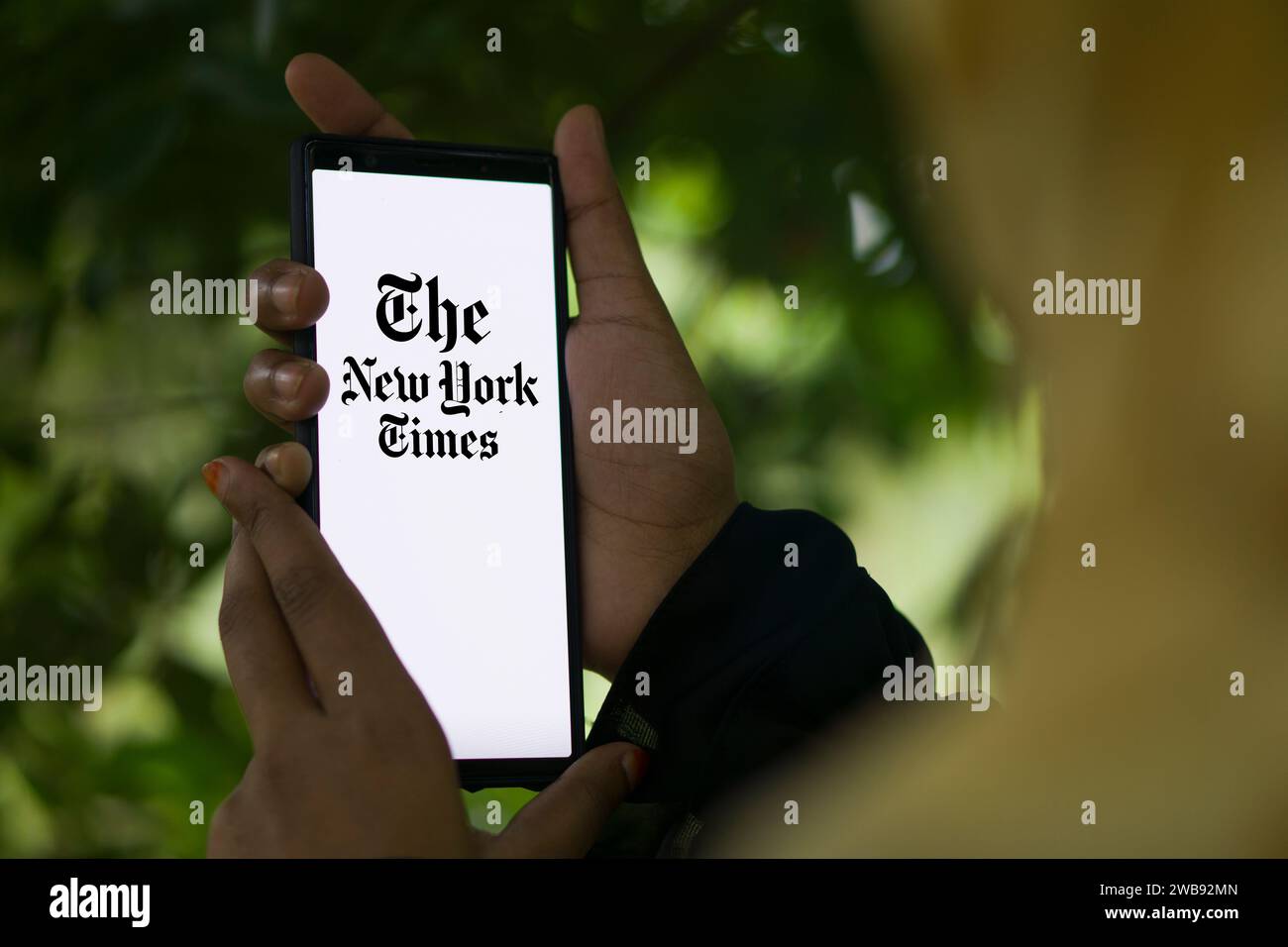 Dhaka, Bangladesh - 09 January 2024: Hands holding a smartphone with The New York Times logo on the screen. The New York Times is an American newspaper. Stock Photo