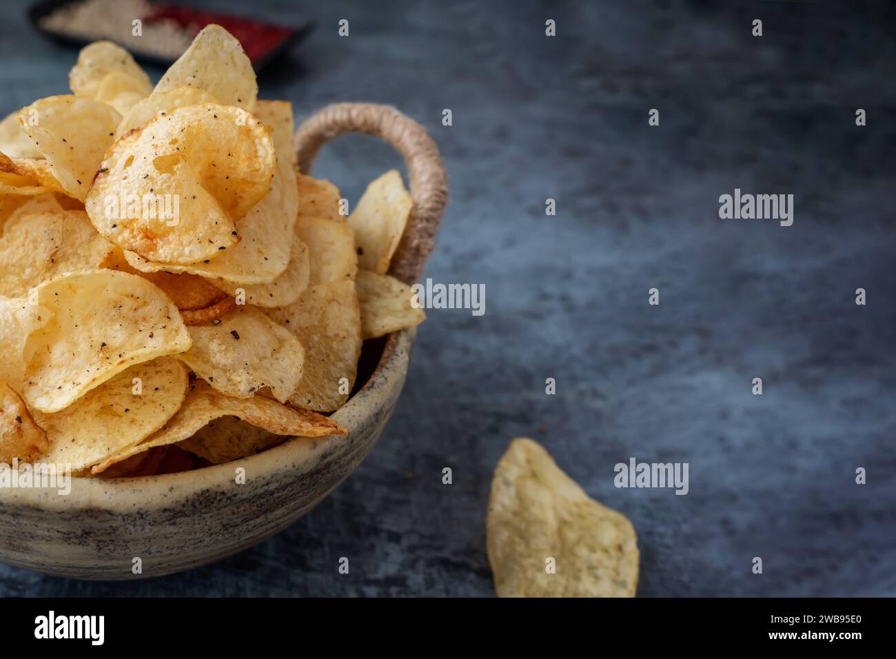 Potato spicy chips in a handmade clay bowl with peppers. Close-up, copy space Stock Photo