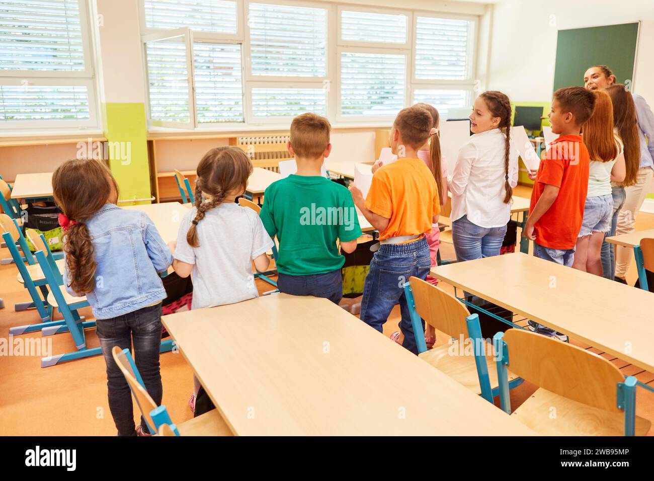 Rear view of male and female students standing side by side with teacher during activity in class Stock Photo