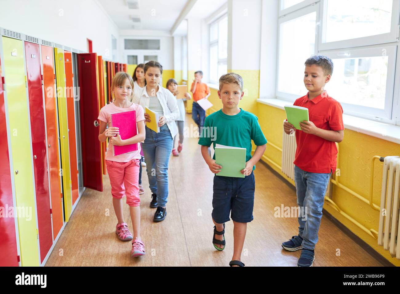 Group of elementary schoolkids walking with books near lockers in ...