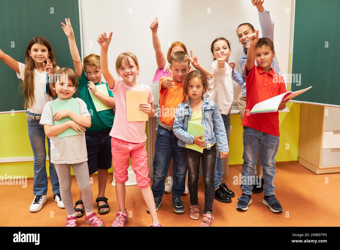Portrait of happy school kids gesturing with teacher in classroom Stock Photo