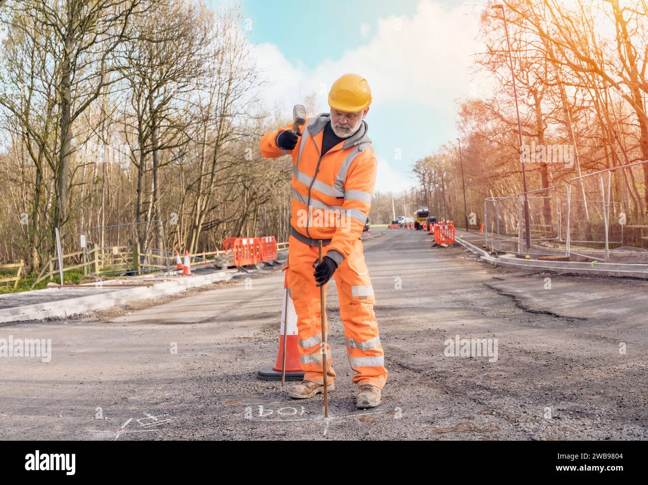 Builder knocking down road setting out steel pins with lump hammer