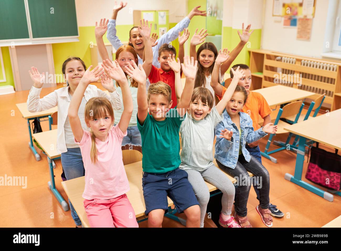 Portrait of cheerful male and female students having fun with teacher in classroom at school Stock Photo