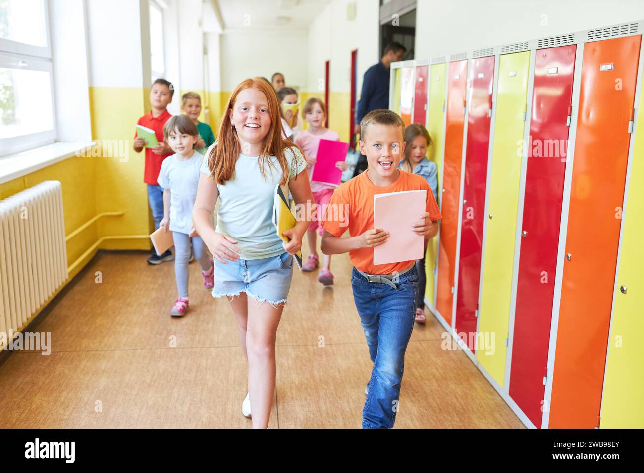 Group of elementary school children running in hallway during recess to their lockers Stock Photo