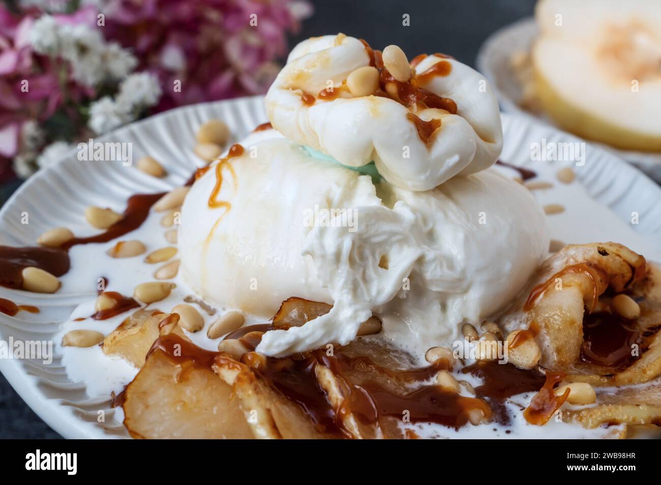 burrata is served with roasted caramelized pear and pine nuts. Close-up. Stock Photo