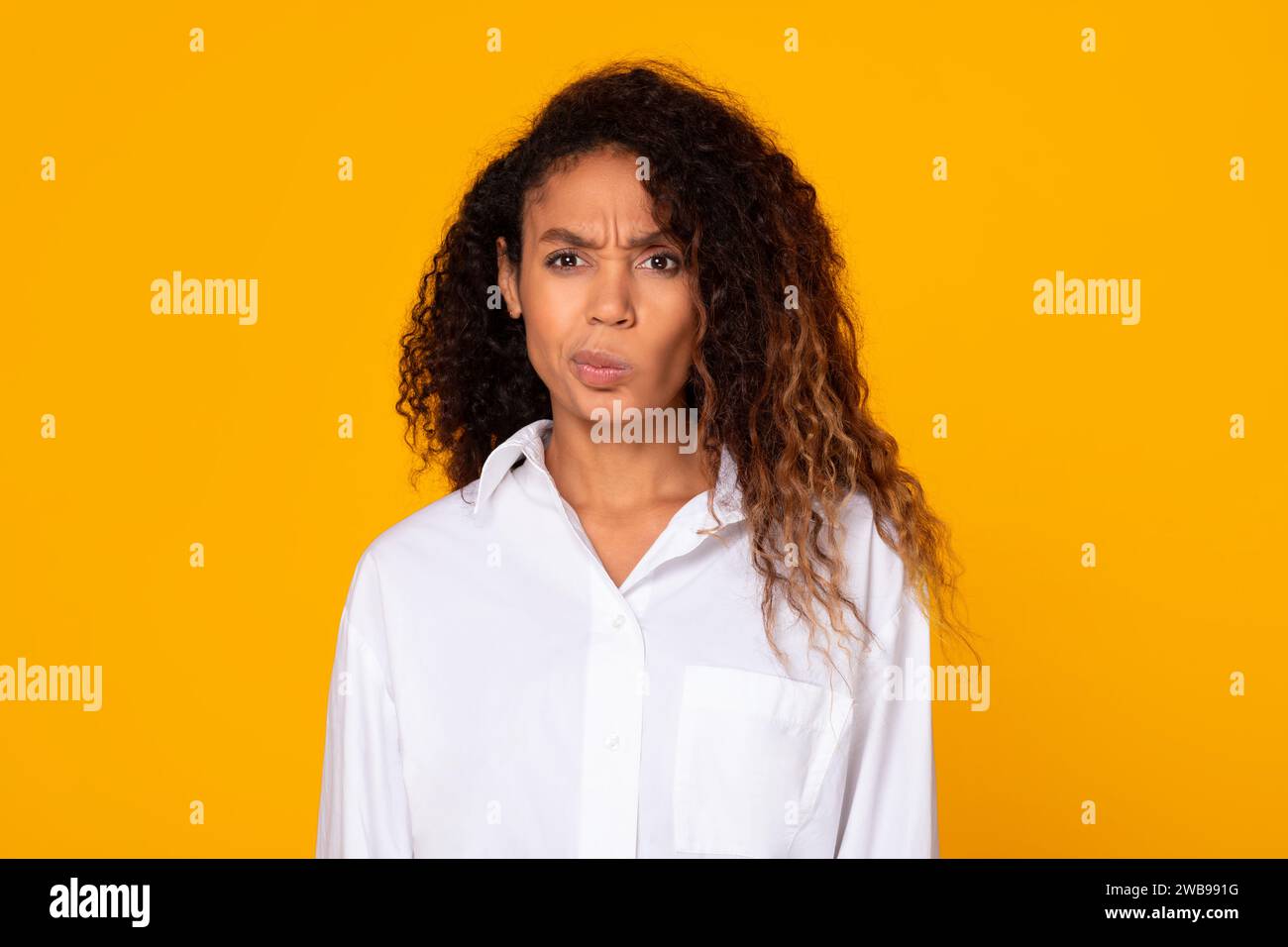 Black young lady frowning in confusion looking at camera, studio Stock Photo