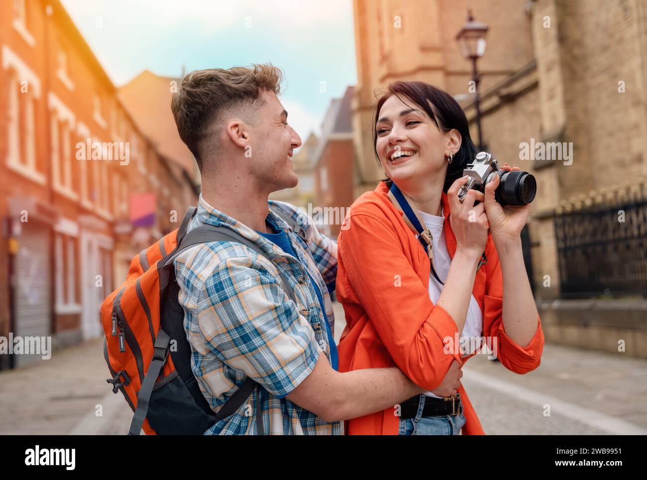 two friend, couple using a camera,   taking selfie against a red phonebox, watching photos on camera, having a fun  in the city of England.Travel Life Stock Photo