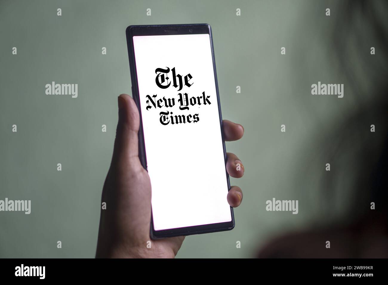 Dhaka, Bangladesh - 09 January 2024: Hands holding a smartphone with The New York Times logo on the screen. The New York Times is an American newspaper. Stock Photo