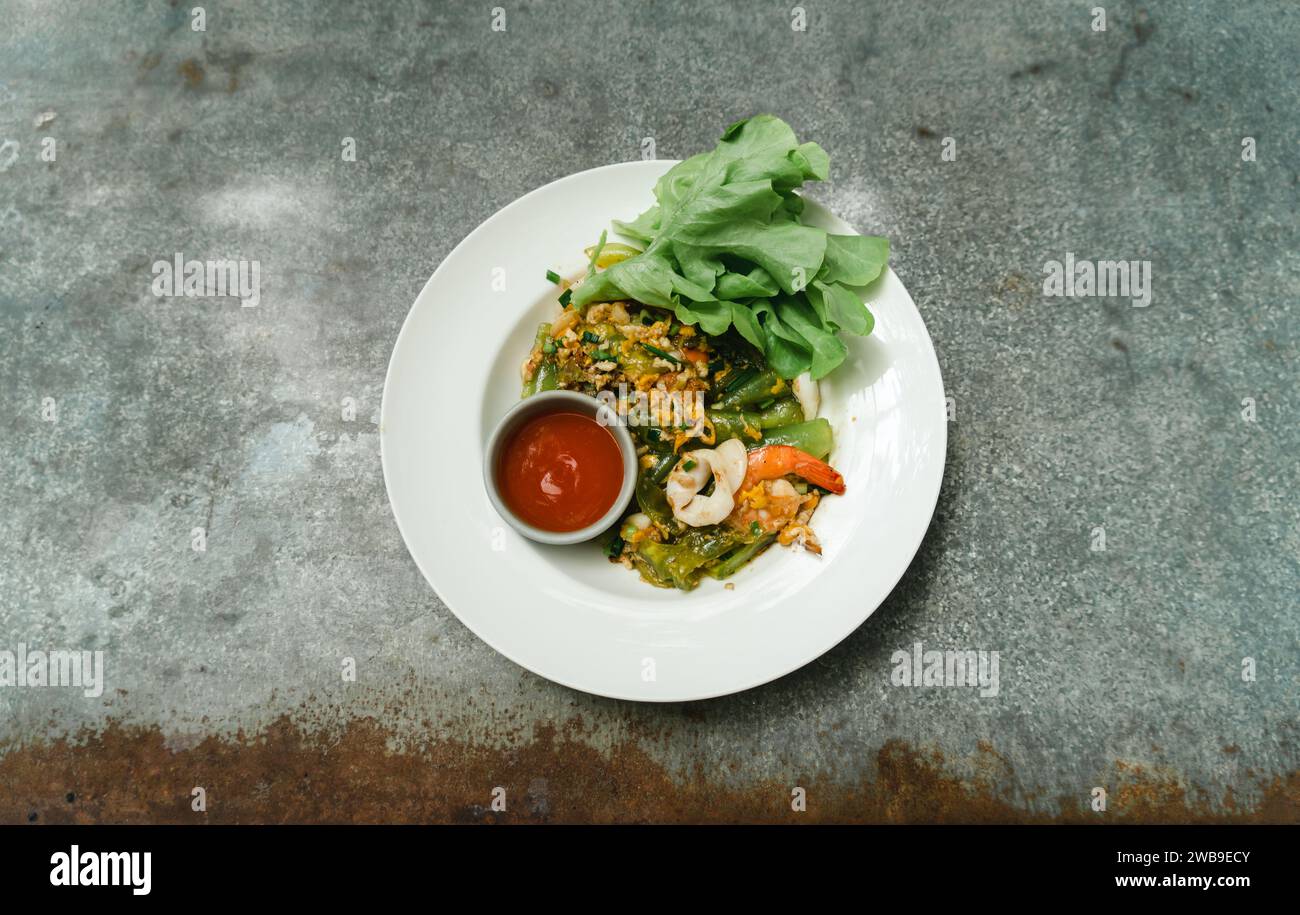 Stir-Fried Spicy Shanghai Noodle with Seafood. Stir fried rice flour (Shanghai noodles) with prawn (shrimp),carrot, long bean, cabbage and chili on wh Stock Photo