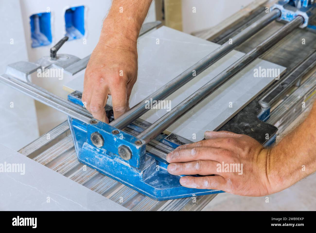 Using tile cutting hand machine, construction worker cuts ceramic tile. Stock Photo