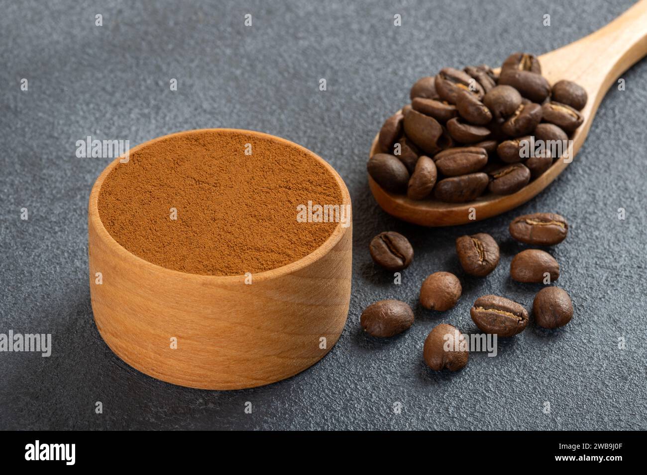 Coffee beans with a bowl of ground coffee on black background Stock Photo