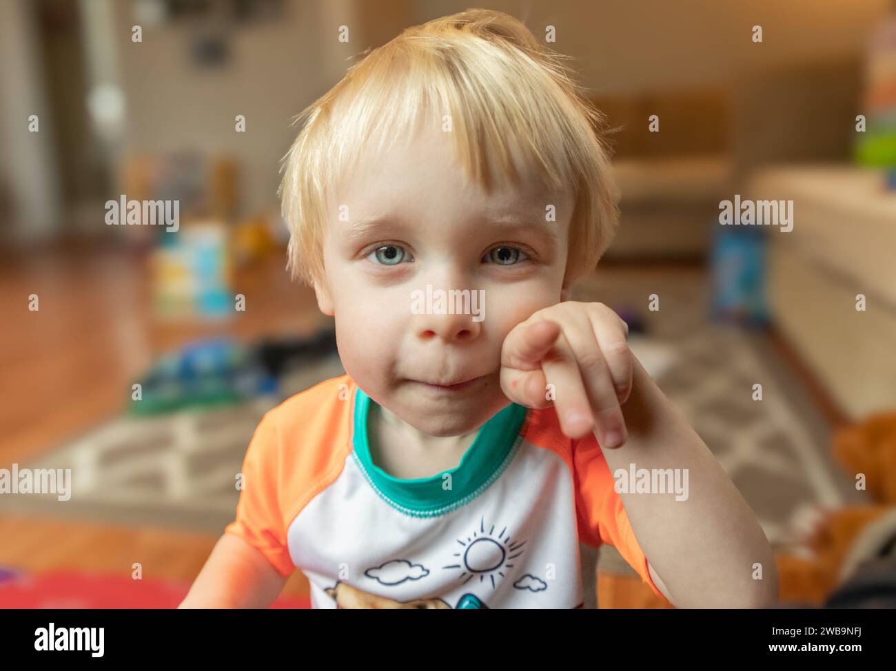 Portrait of a blond-haired, blue-eyed, curious and impish toddler. Stock Photo
