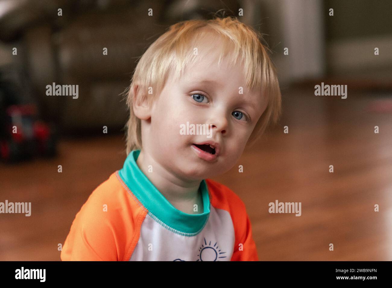 Portrait of a blond-haired, blue-eyed, curious and impish toddler. Stock Photo