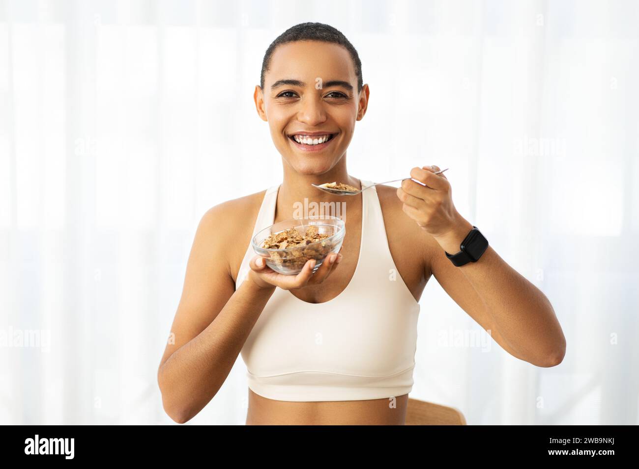 Radiant black woman enjoying a bowl of healthy cereal, wearing a