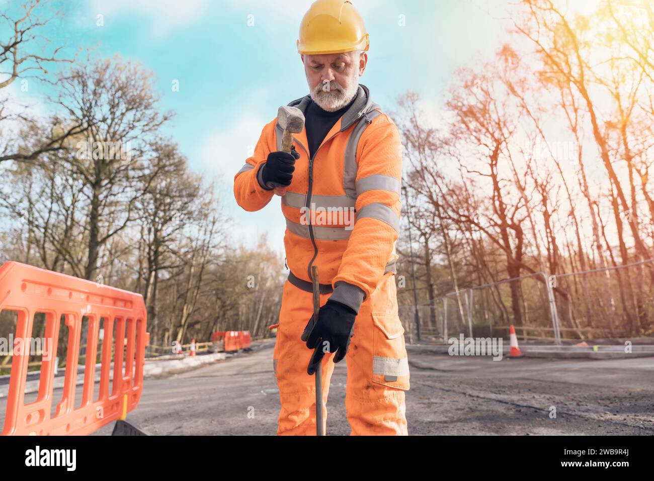 Builder knocking down road setting out steel pins with lump hammer