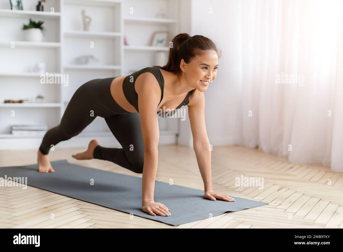 Happy young asian woman doing yoga lunge exercise at home Stock Photo ...