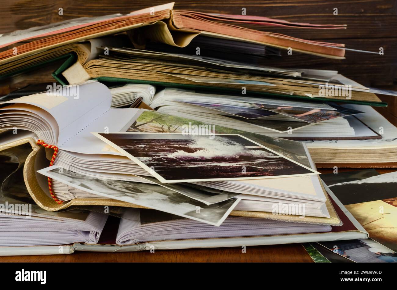 Nostalgia - old family photo albums and photos lie a heap on a wooden table. Stock Photo