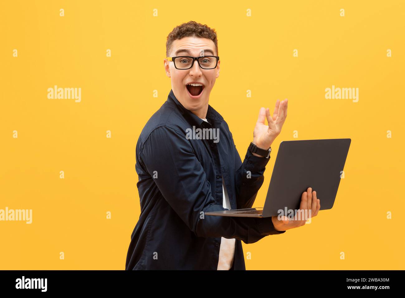 Amazed young man in eyeglasses using laptop computer Stock Photo