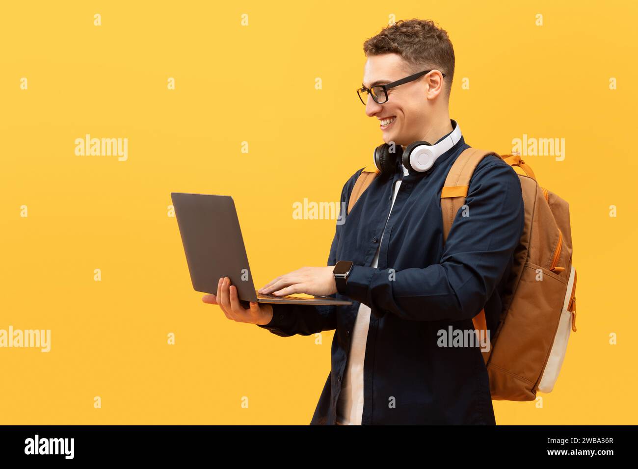 Cool young guy student with backpack using laptop Stock Photo