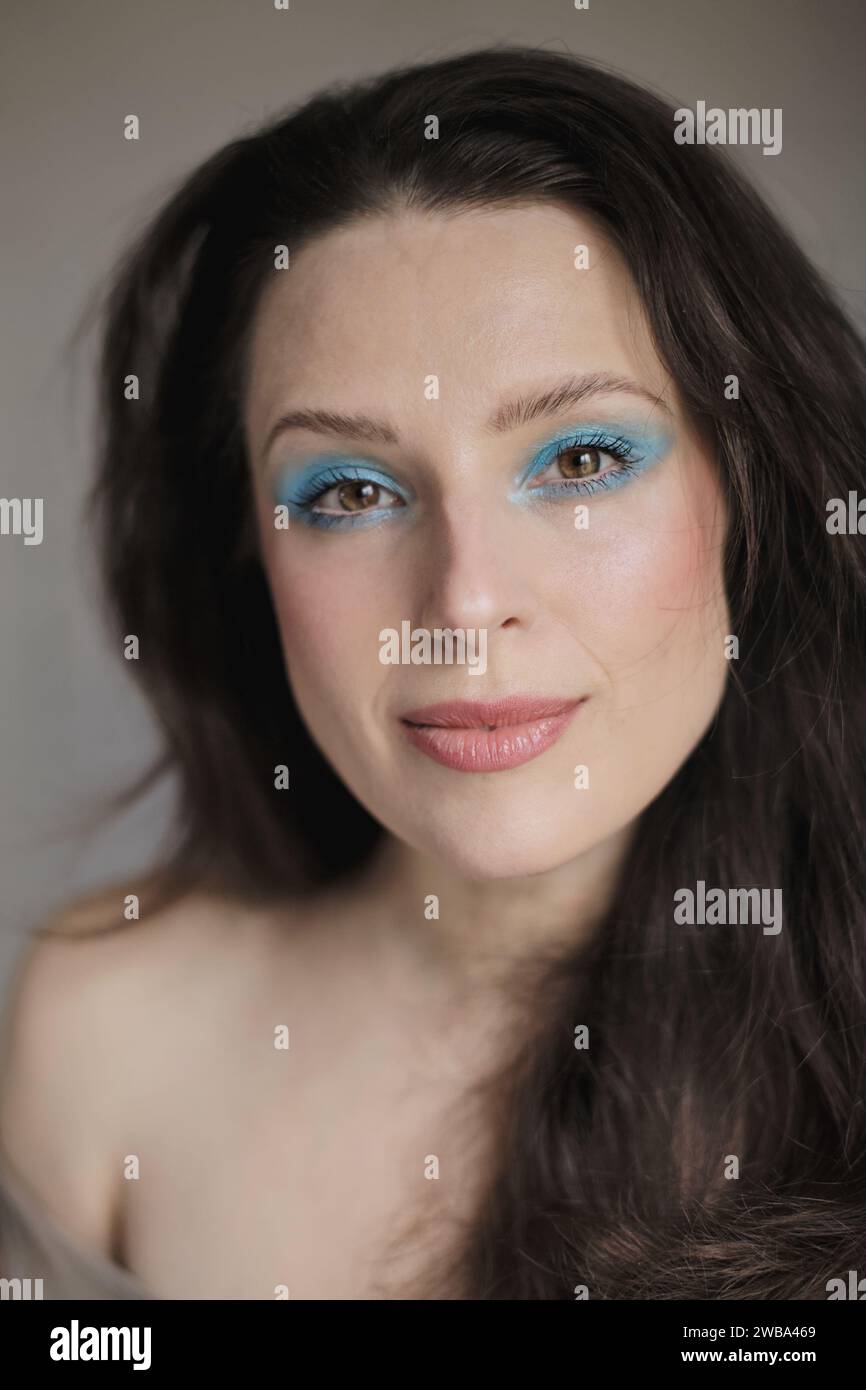 Portrait of a woman wearing bright light blue eyeshadow shade and her ...