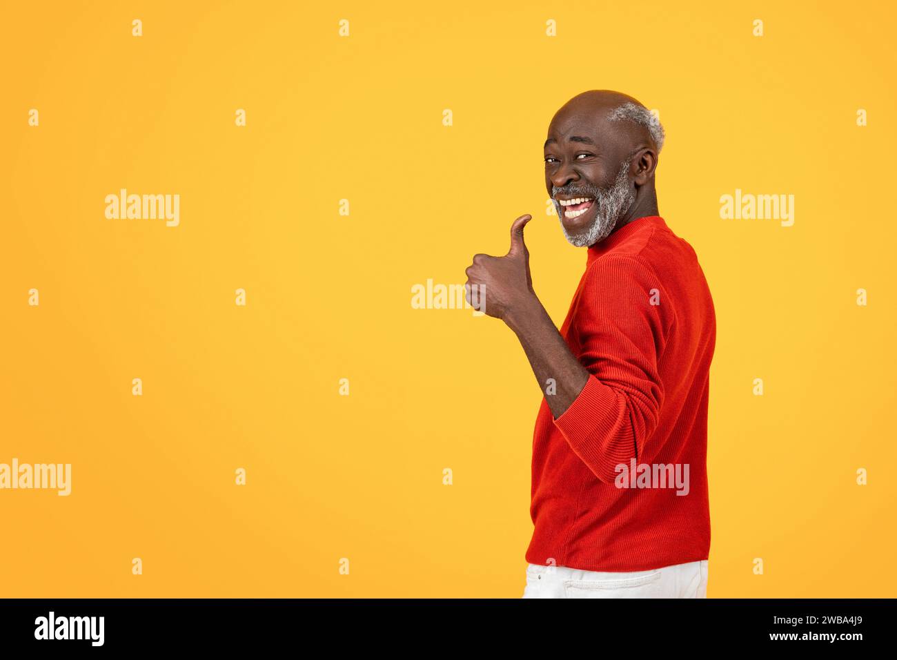 Enthusiastic senior Black man with a white beard giving a thumbs up sign, turning back with a big smile Stock Photo