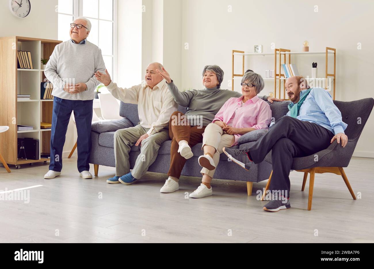 Group of happy senior people sitting on couch and watching sports match on television Stock Photo