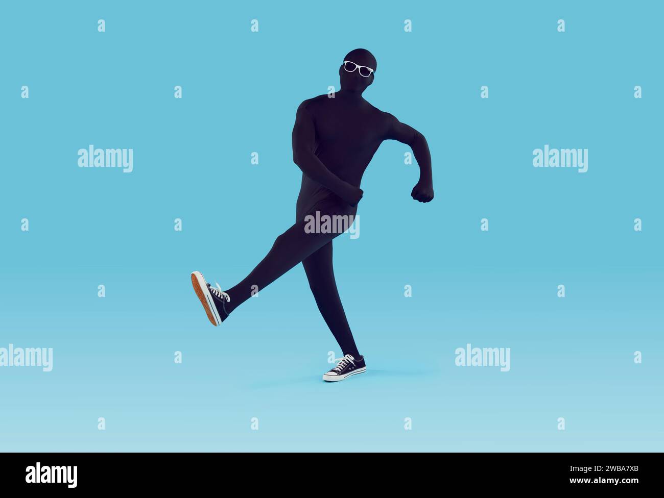 Happy man in black spandex bodysuit dancing or walking in funny way on blue background Stock Photo