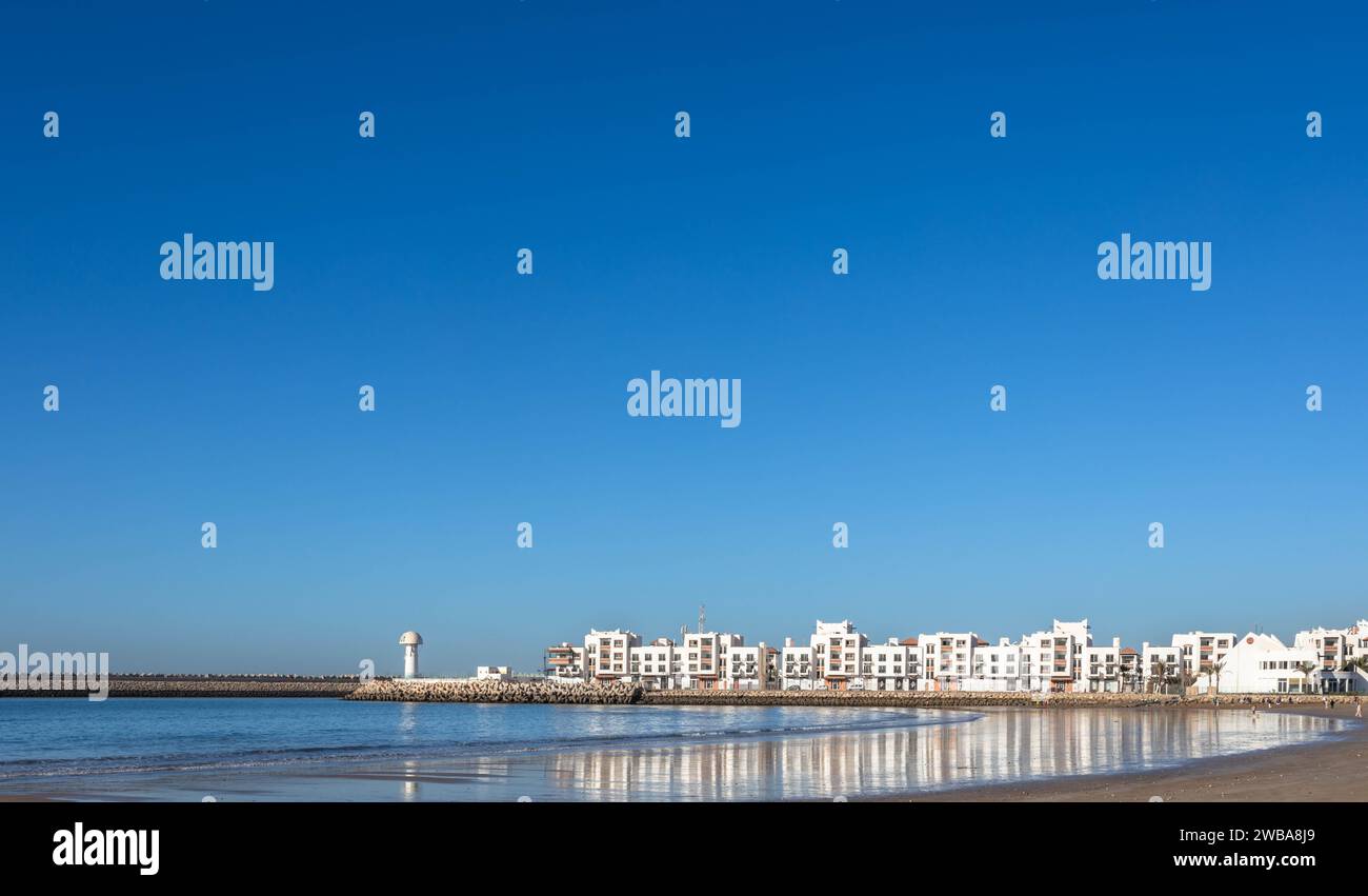 View of beach and curve of Atlantic Ocean, with buildings of Marina and big, blue sky Stock Photo